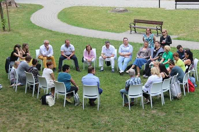 Imagen de personas reunidas en círculo sobre un césped, discutiendo ideas