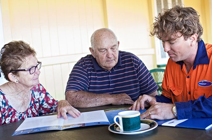 A person from Powerlink discussing with two elderly people
