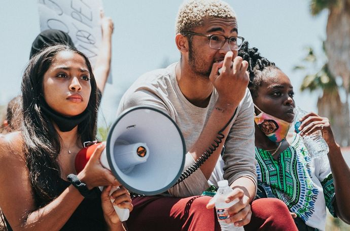 Personas con un megáfono y carteles de protesta