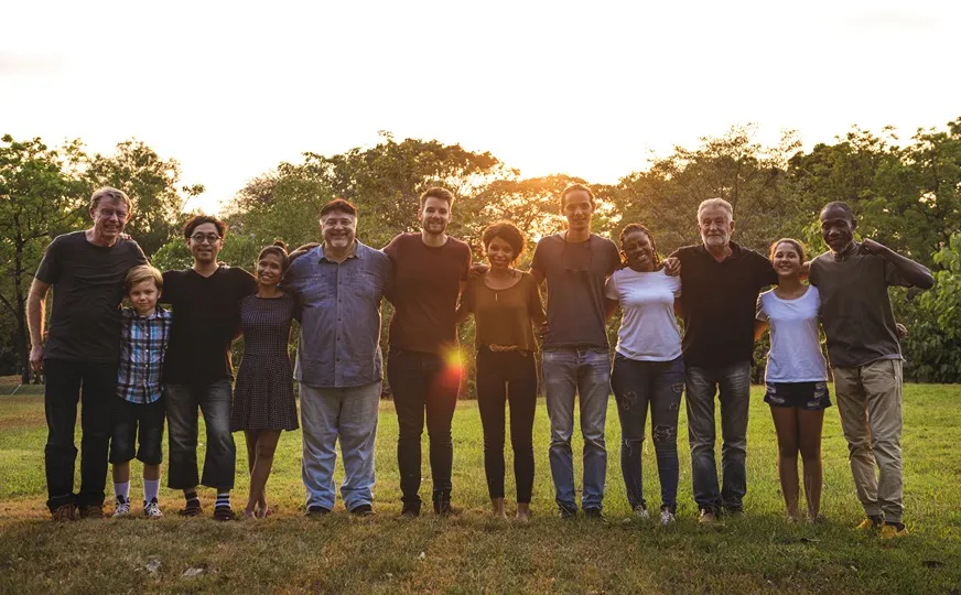 Personas de pie en un campo con los brazos sobre los hombros de los demás