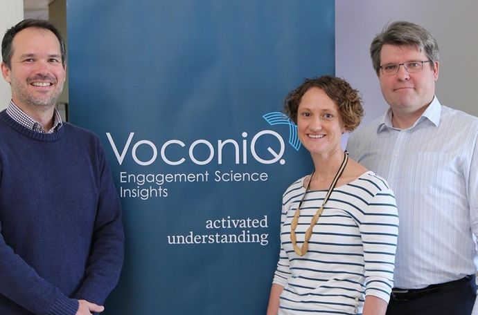 Voconiq co-founders standing in front of a banner